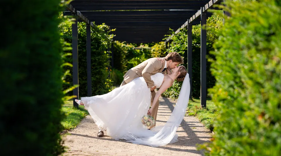 Brudepar danser under en grøn pergola