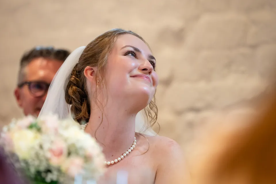 Brud med perlekæde smiler op under talerne